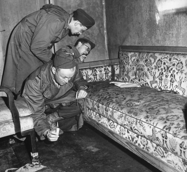Soldados soviéticos examinan el sofá en el que se suicidaron Hitler y Eva Braun.