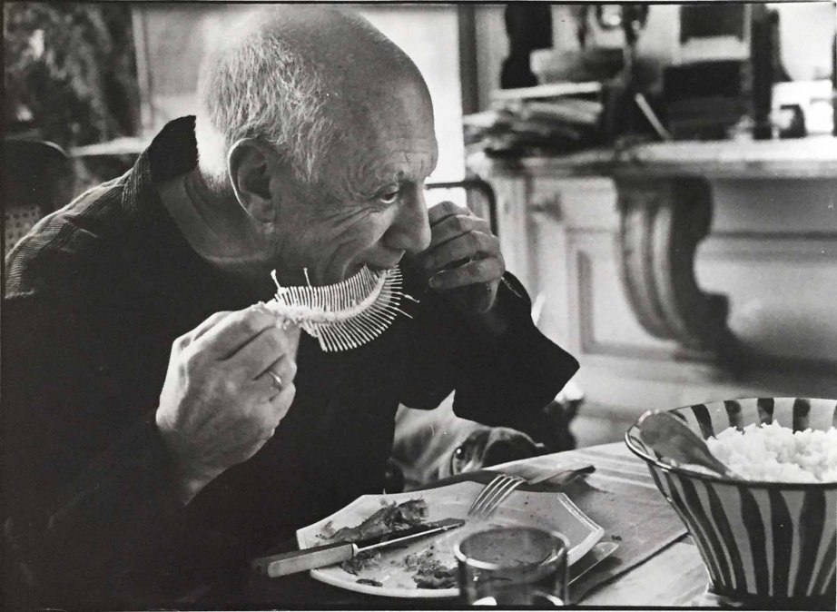 Picasso comiendo un pescado cuyo esqueleto será moldeado en arcilla, por David Douglas Duncan, abril de 1957, Villa La Californie (Cannes).