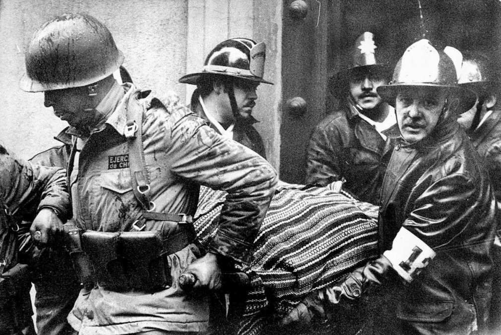  Soldados y bomberos portan el cuerpo del  presidente Salvador Allende, envuelto en un poncho boliviano, del  destruido palacio presidencial La Moneda.