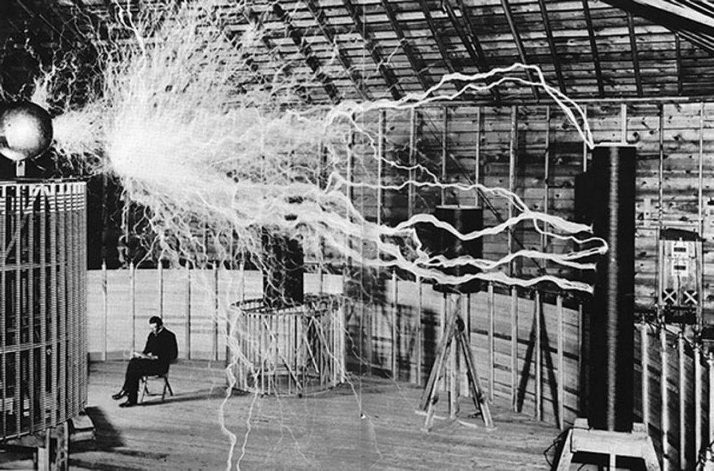 Nikola sentado al lado de una bobina de Tesla, en su laboratorio de Colorado Springs 