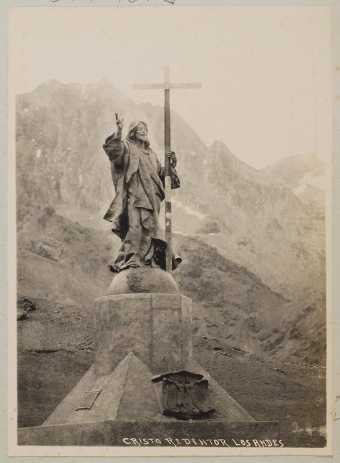 Cristo bendiciendo con su mano derecha, mientras sostiene una gran cruz, parado sobre un hemisferio terráqueo.